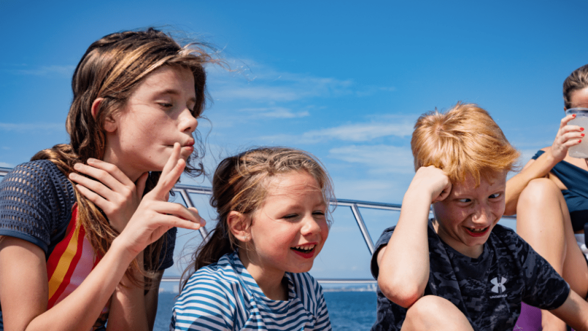a group of young children sitting next to a body of water